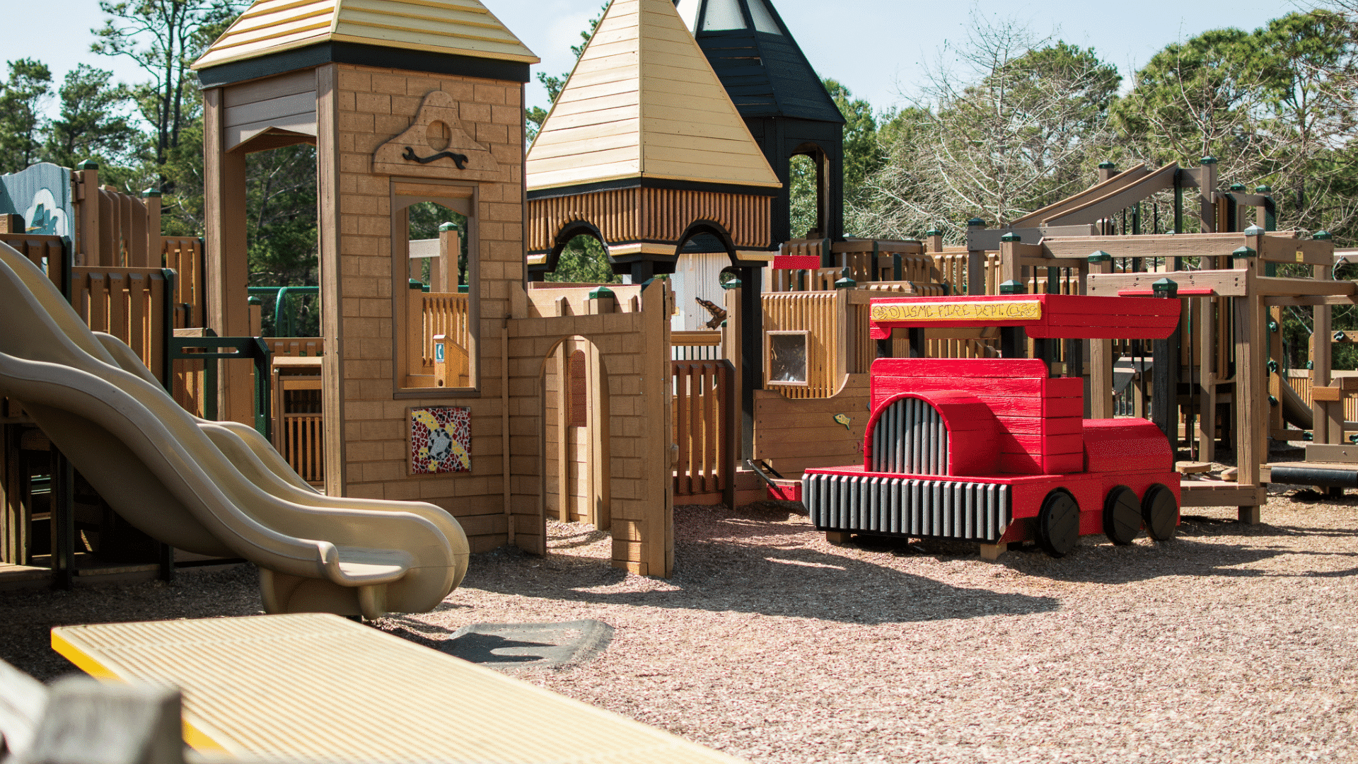 a playground with a red train and a slide - Perdido Kids Park